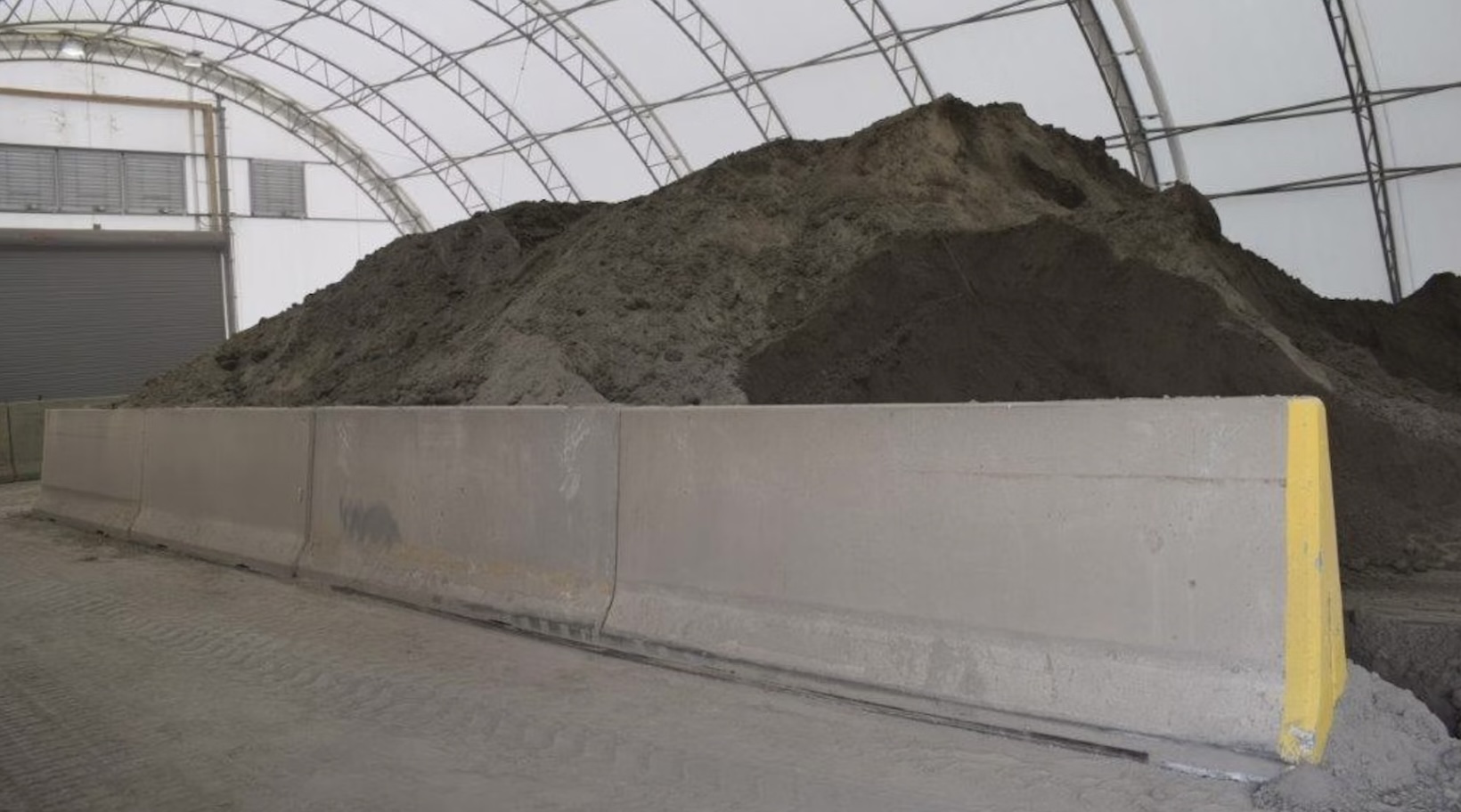 Mound of fly ash behind concrete barrier